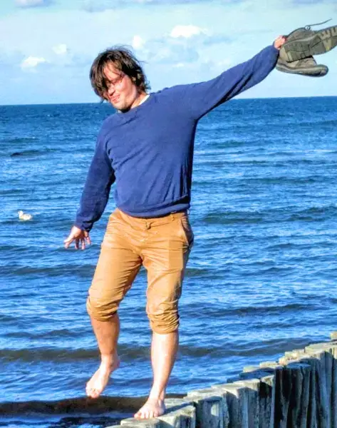 David_Riemay balanciert auf einem Holzsteg am Strand