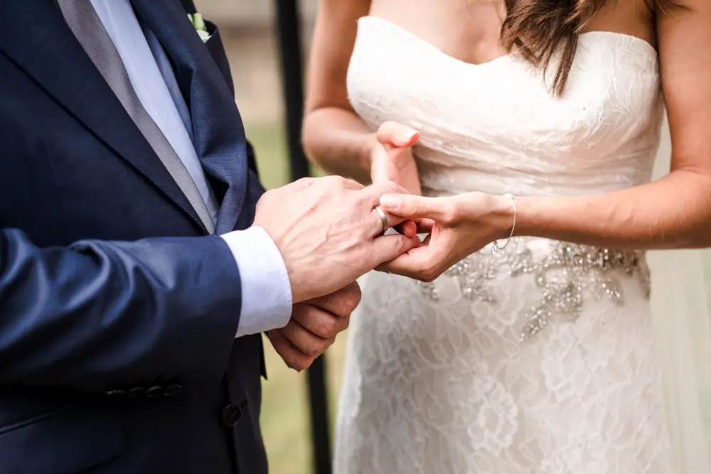 Ist eine freie Trauung rechtskraeftig? Ein Hochzeitspaar steckt sich während der freien Trauung die Ringe an.