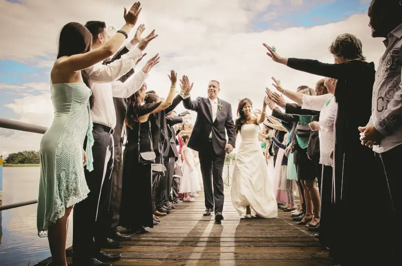 Brautpaar zieht auf einem Steg aus nach einer freien Trauung und die Gäste bilden einen Spalier